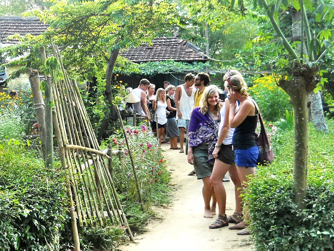 Visitors walking the flower-lined garden path through the village