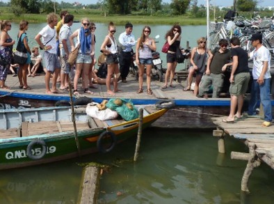 Visitors disembarking from wooden boats at the village landing