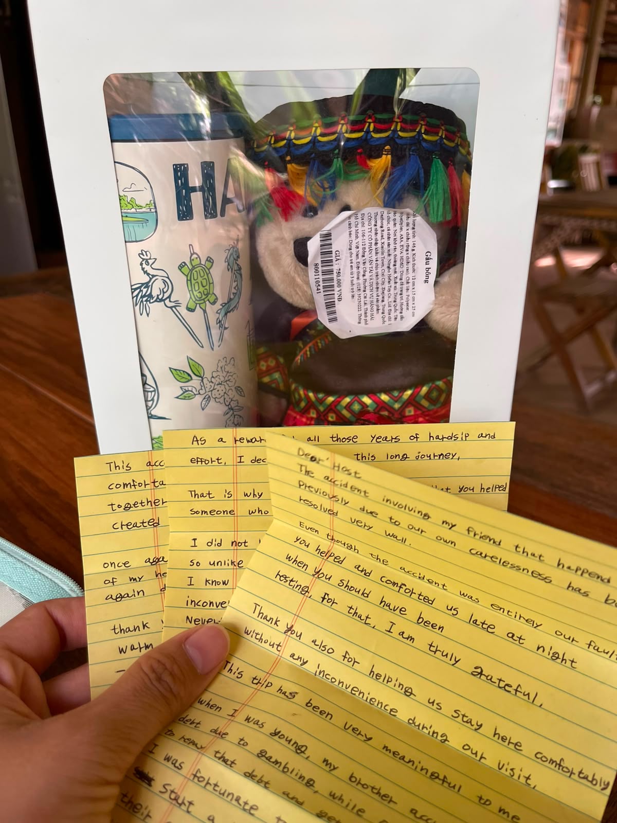 Several handwritten notes held in hand beside a wrapped gift left by guests
